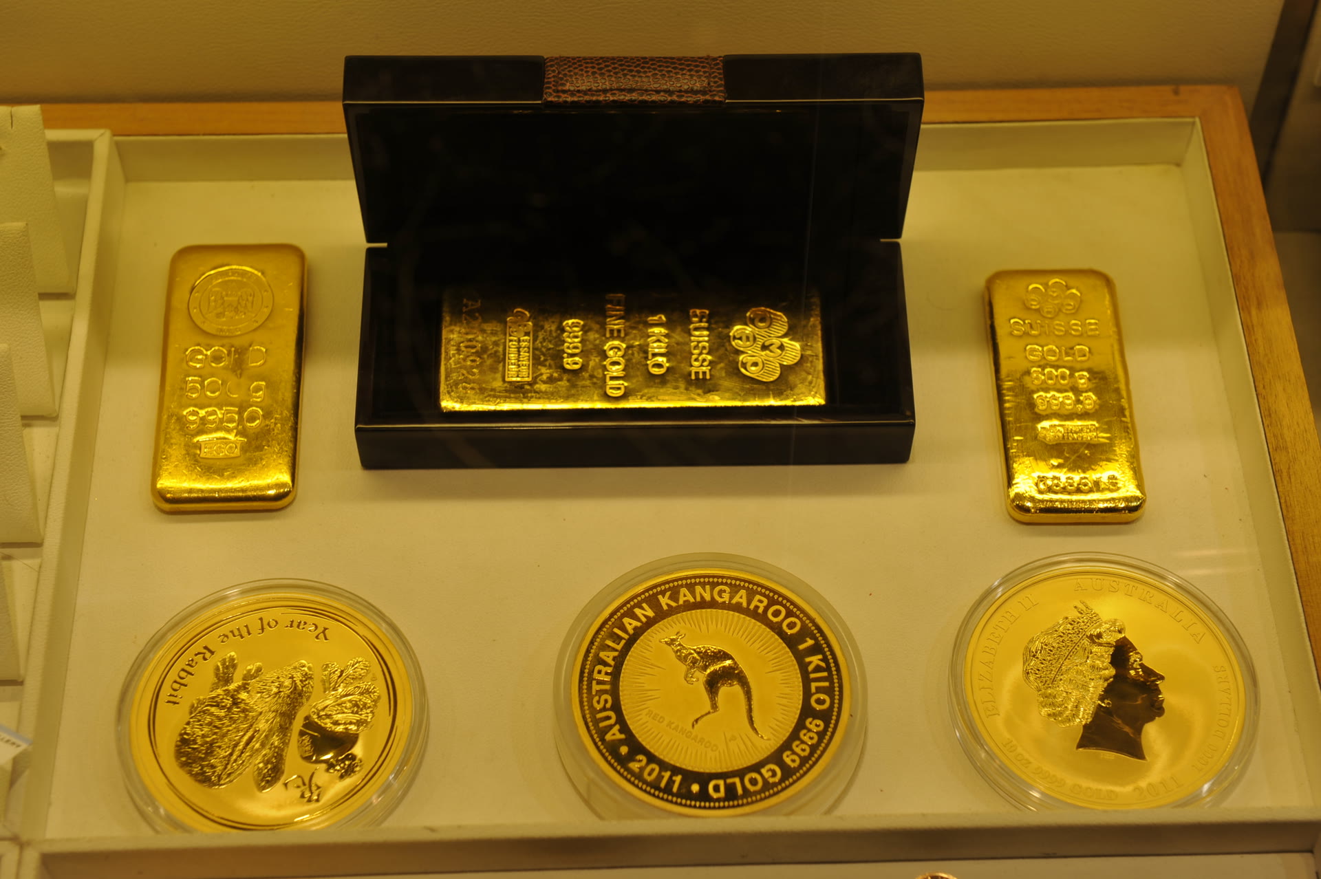 Gold bars and Perth Mint 1 kilo Kangaroo and Lunar gold coins in a dealer's display cabinet